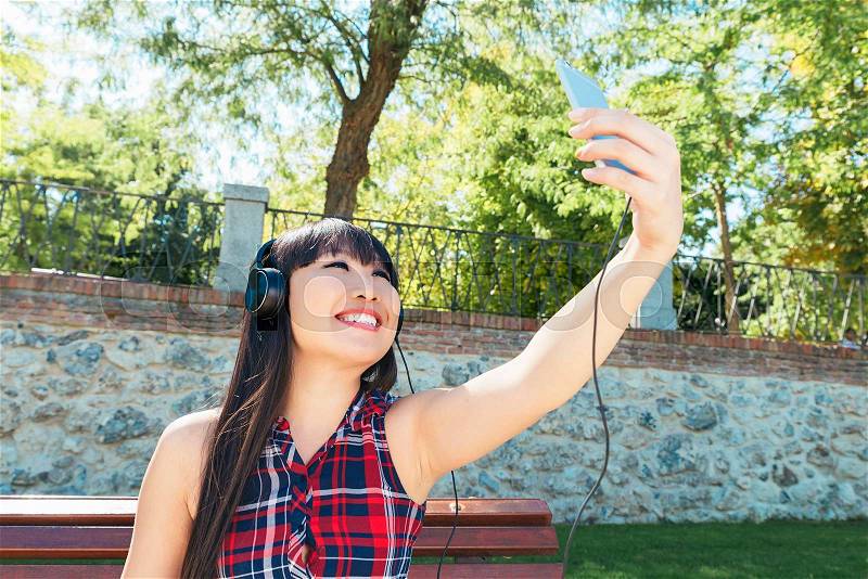 Asian woman taking self portrait selfie photo on park. She is happy, stock photo