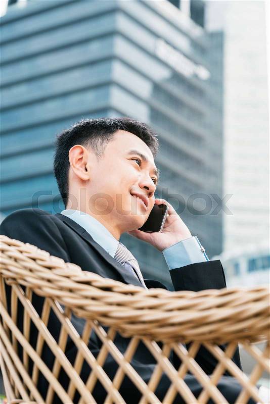 Handsome business man speaking mobile phone at his company office building, model is a asian male, stock photo