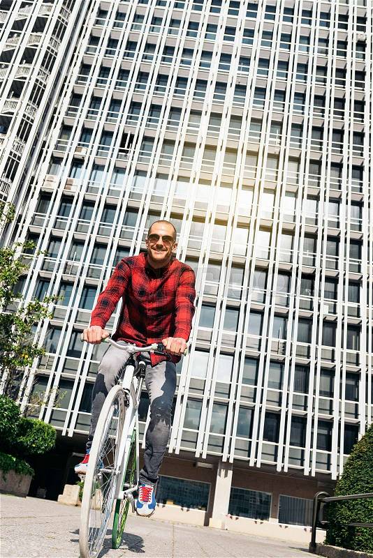 Handsome young man on bike in the city. Bicycle concept, stock photo
