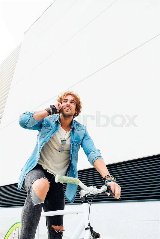 Handsome young man with mobile phone and fixed gear bicycle in the street, stock photo