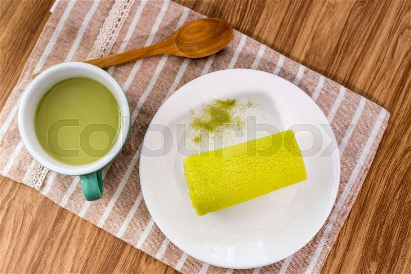 Roll cake with green tea on wooden table, stock photo