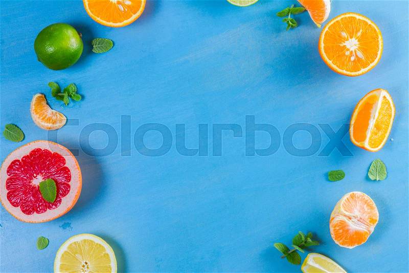 Citrus food close up frame pattern on blue background - assorted citrus fruits with mint leaves, stock photo