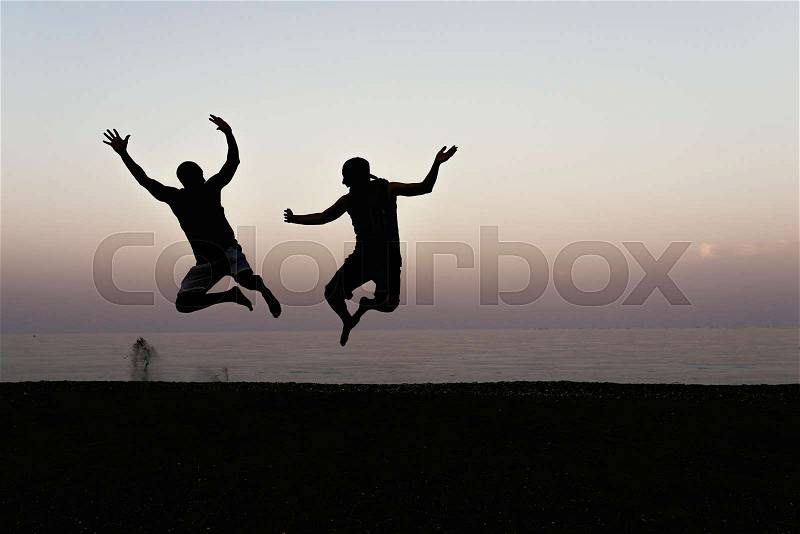 Happy of two friends jumping and sunset in the beach, stock photo