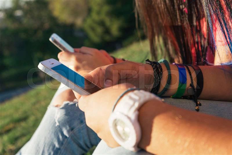 Two friend hands texting in their smartphones in the park, stock photo