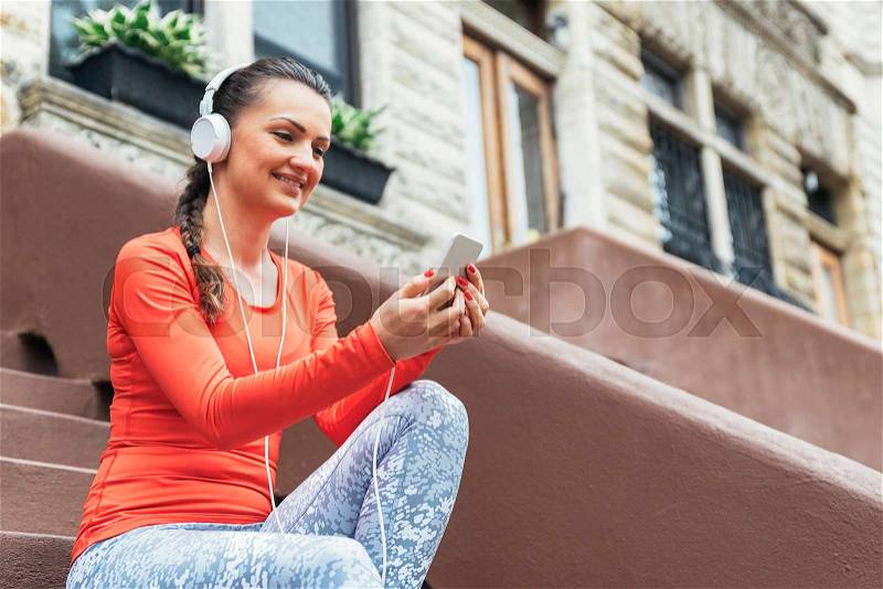 Beautiful woman using phone after running on New York City, stock photo