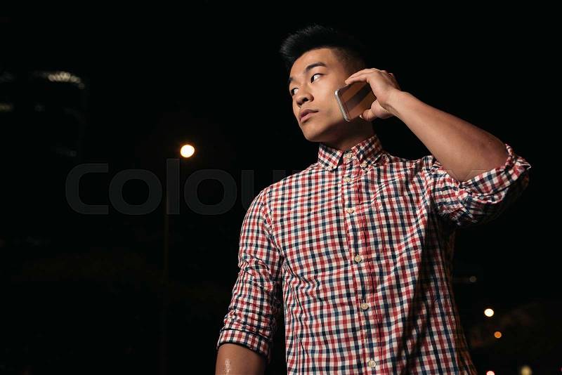 Handsome asian young man with mobile phone in the city, stock photo