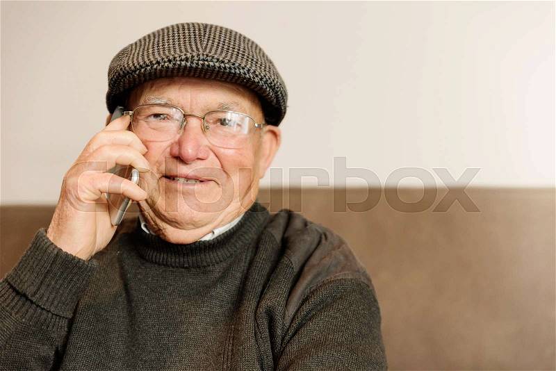 Senior man using his mobile phone at home, stock photo