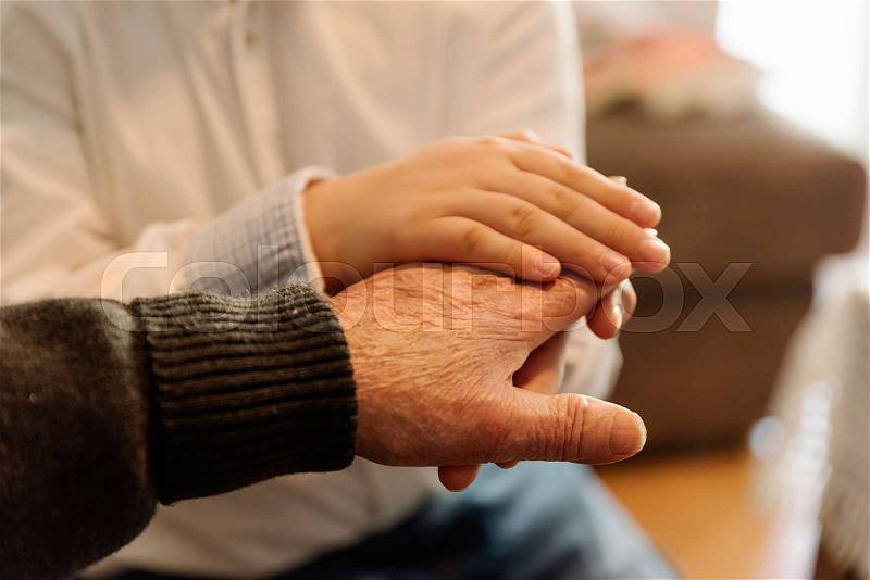 Hand of old person holding hand of kid. Old Age Concept, stock photo