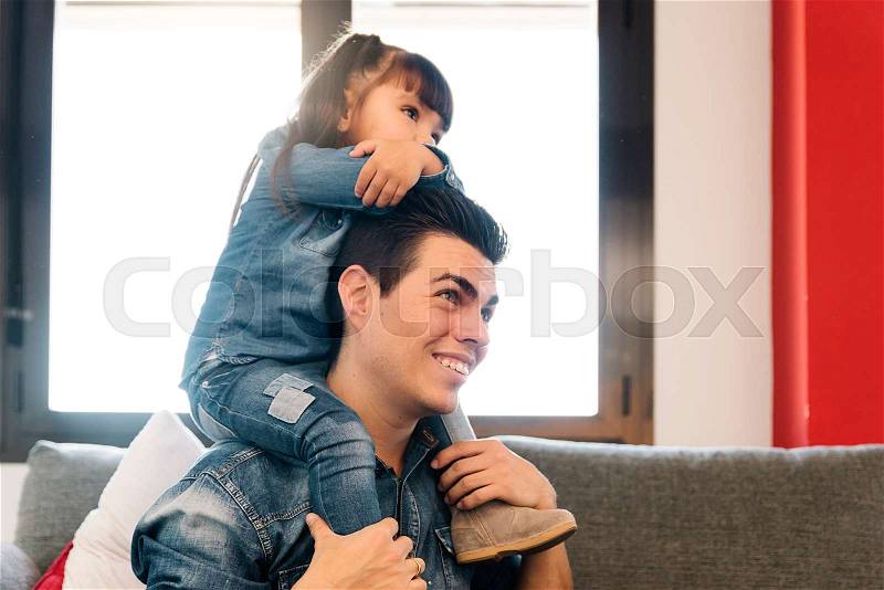 Proud father piggybacking his daughter at home. , stock photo