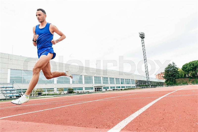 Attractive man Track Athlete Running On Track. He is on stadium, stock photo