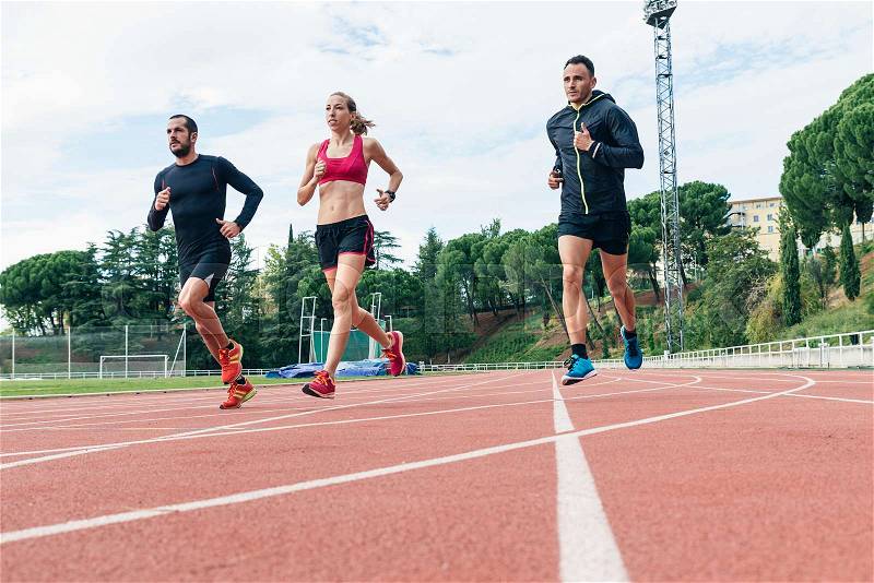 Group of young athletics people running on the track field, stock photo
