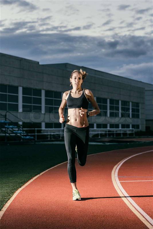 Attractive woman Track Athlete Running On Track. She is looking, stock photo