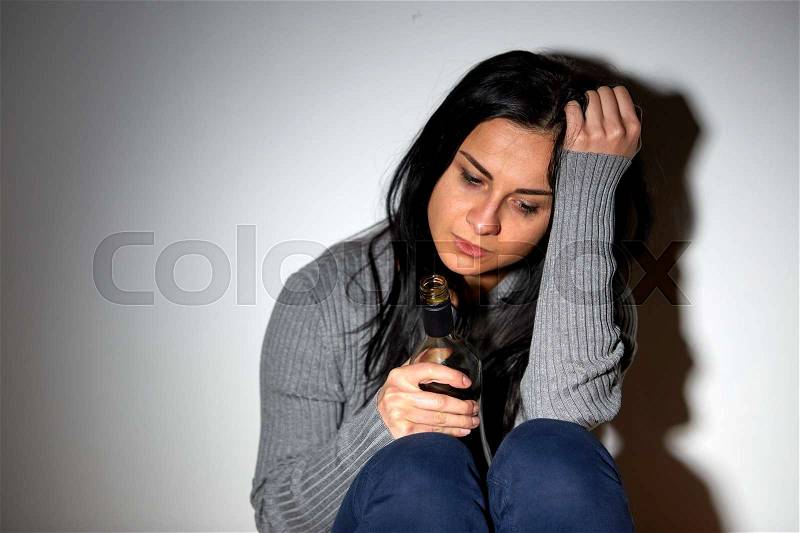 Alcoholism, depression and people concept - unhappy drunk crying woman with bottle of alcohol, stock photo