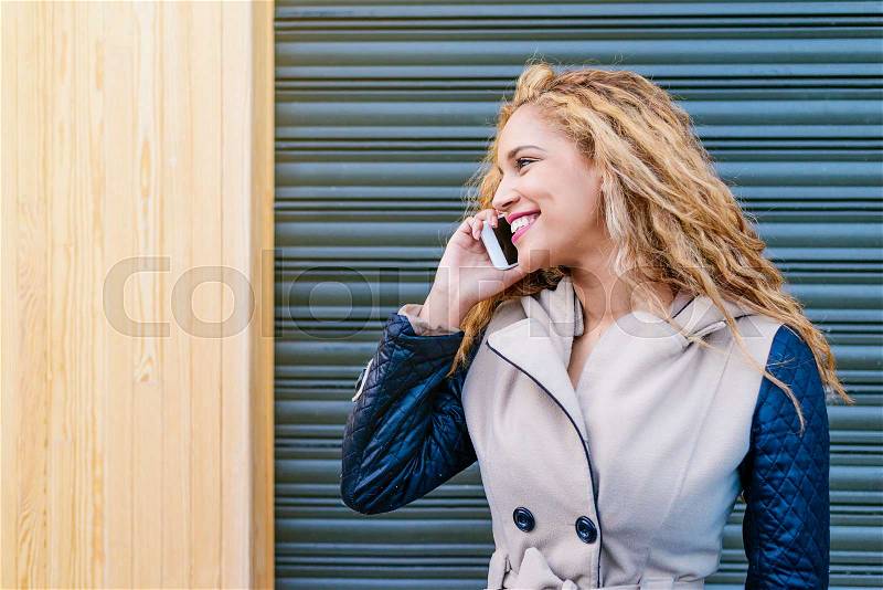 Outdoor portrait of attractive young woman with mobile phone in the street, stock photo