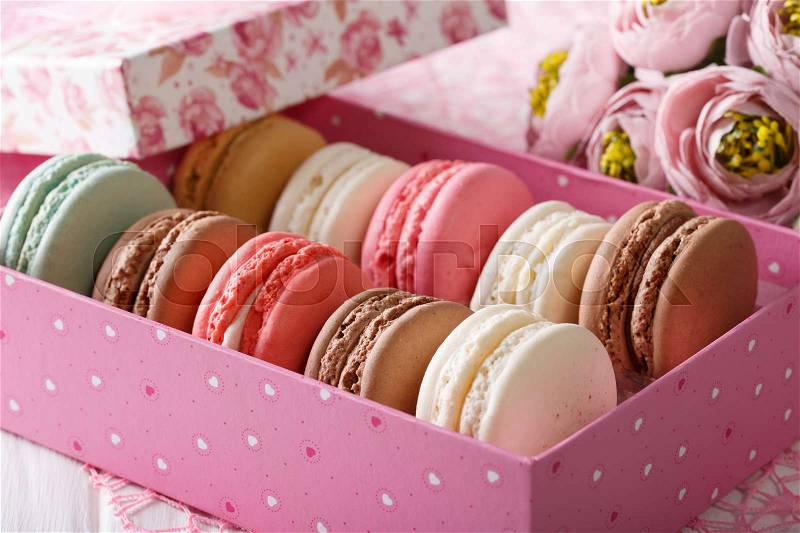French macaroons in a pink box and flowers close-up on a table. horizontal , stock photo