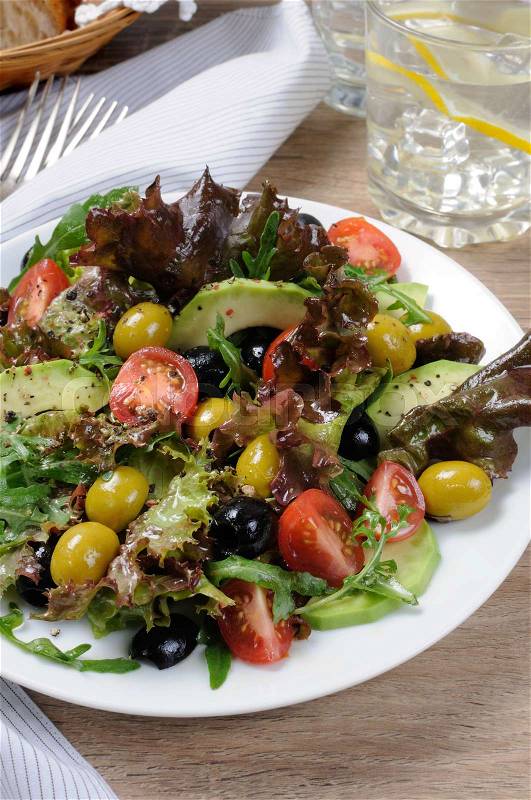 Summer salad - with avocado, olives, tomatoes in lettuce dressed, mustard-garlic sauce, stock photo