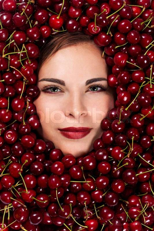 Beautiful woman covered with cherries, close-up face, stock photo