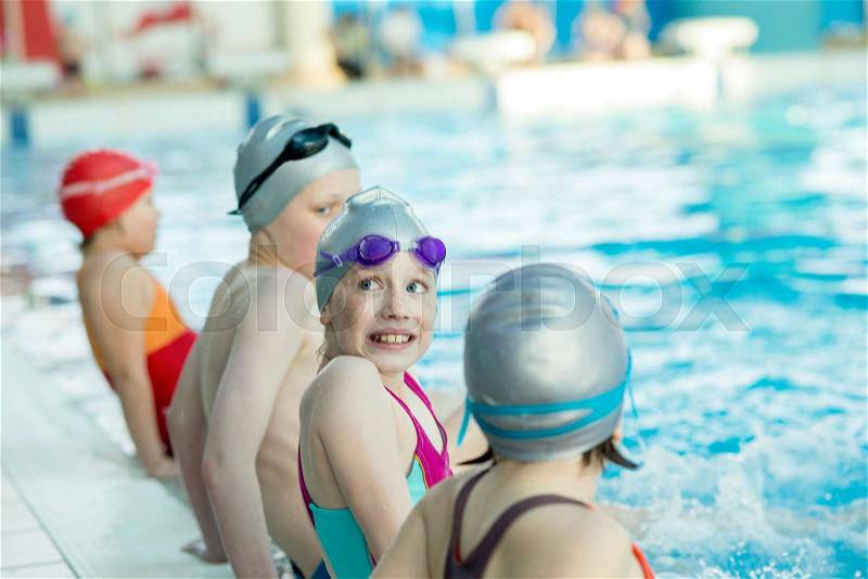 Happy children kids group at swimming pool class learning to swim, stock photo