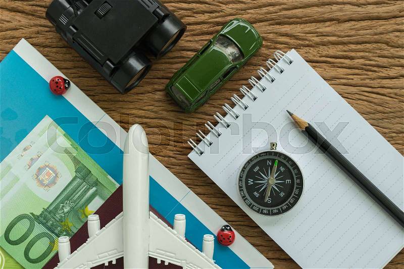Toy airplane, compass, binoculars, pencil, paper note and miniature car on wood table as travel planning road trip concept, stock photo