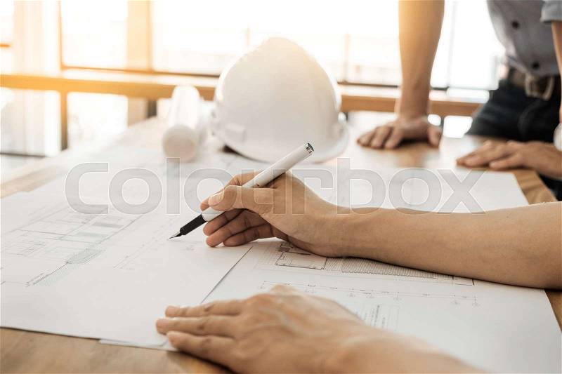 Architects engineer discussing at the table with blueprint - Closeup on hands and project print, stock photo