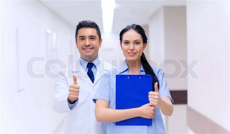 Healthcare, profession, people and medicine concept - smiling doctor and nurse with clipboard showing thumbs up at hospital, stock photo
