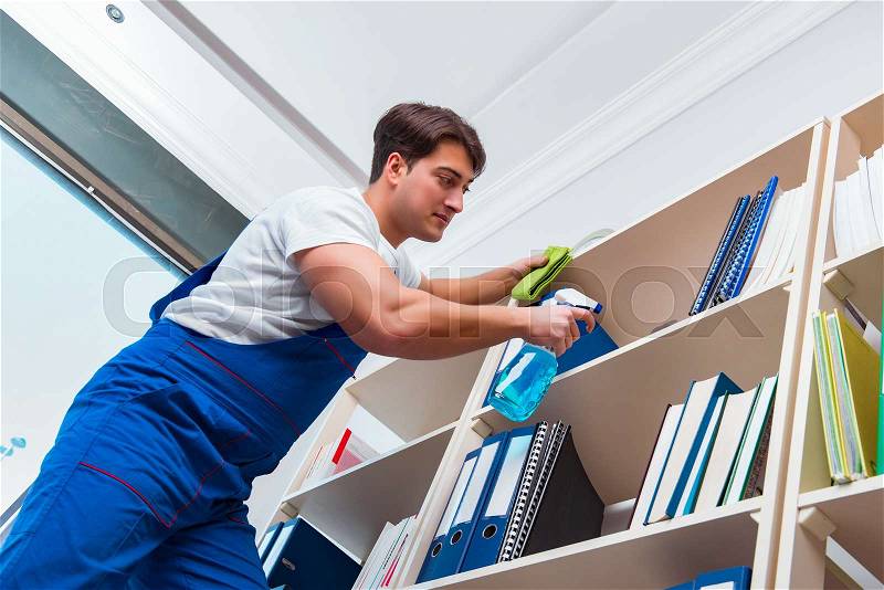 Male office cleaner cleaning shelves in office, stock photo