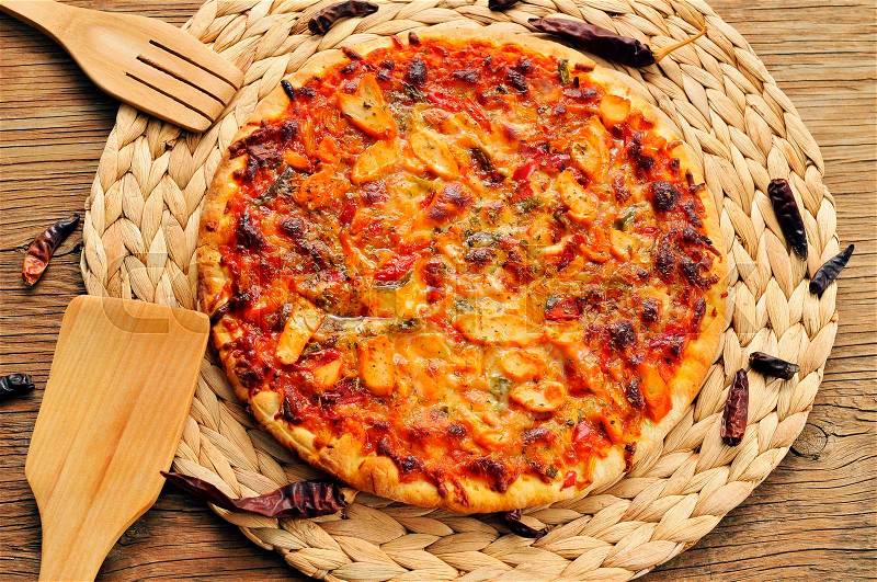 A pizza with chicken, red pepper and green pepper, served on a wooden background, stock photo