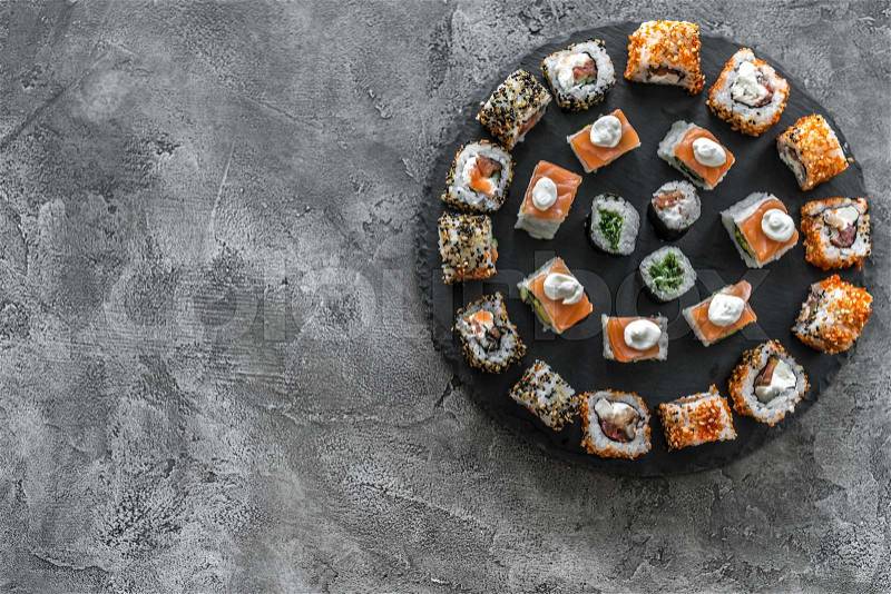 Sushi set on a round board on a concrete background with space for text, stock photo