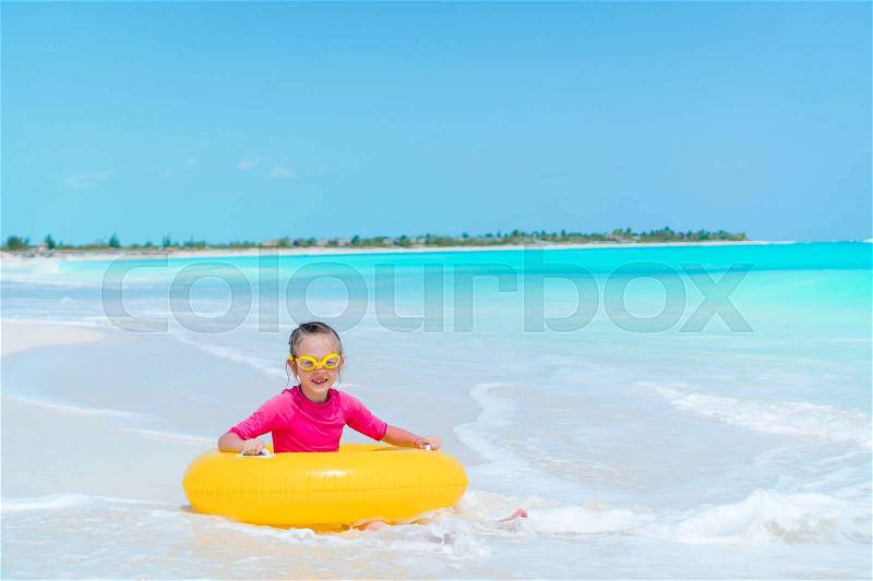 Adorable little girl with inflatable rubber circle splashing. Kid having fun on summer active vacation, stock photo