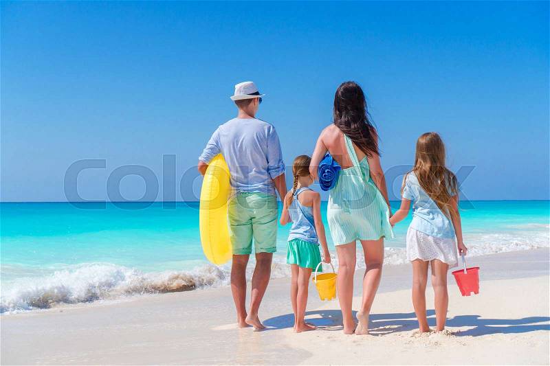 Family travel concept. Rear view of young family with two kids on the seashore, stock photo