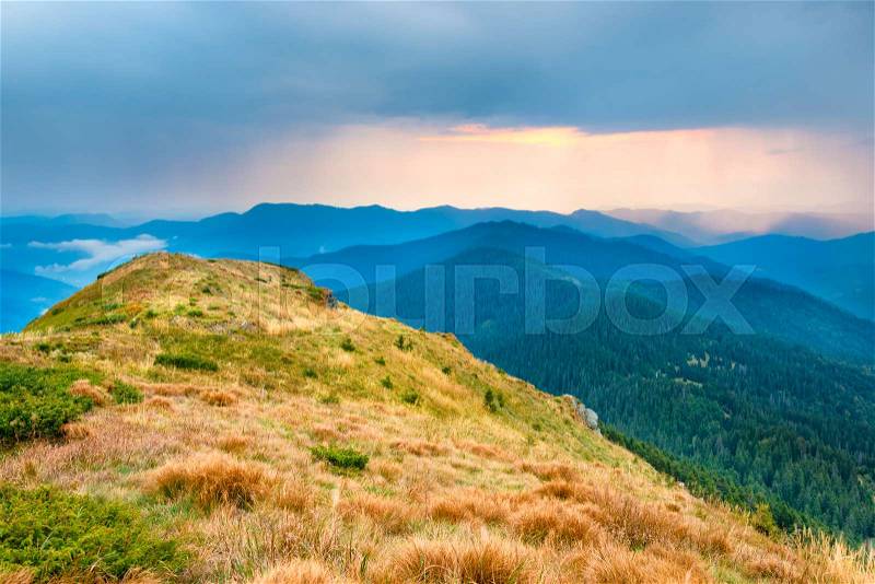 Sunset over mountains and hills with dry yellow grass, stock photo
