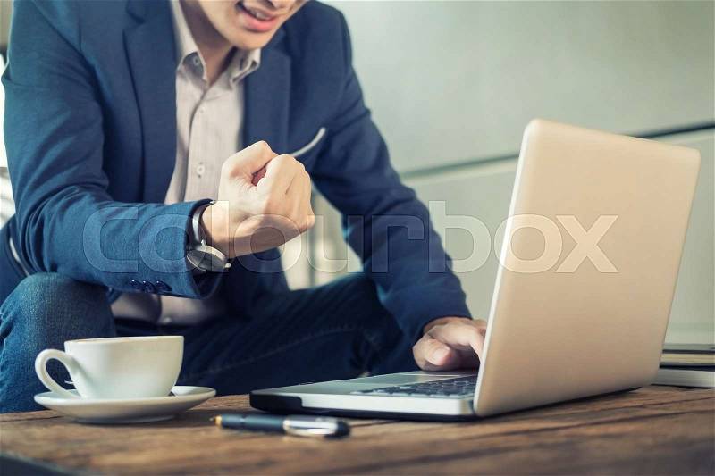 Satisfied with work done. Happy young man working on laptop while sitting at coffee shop or cafe, stock photo