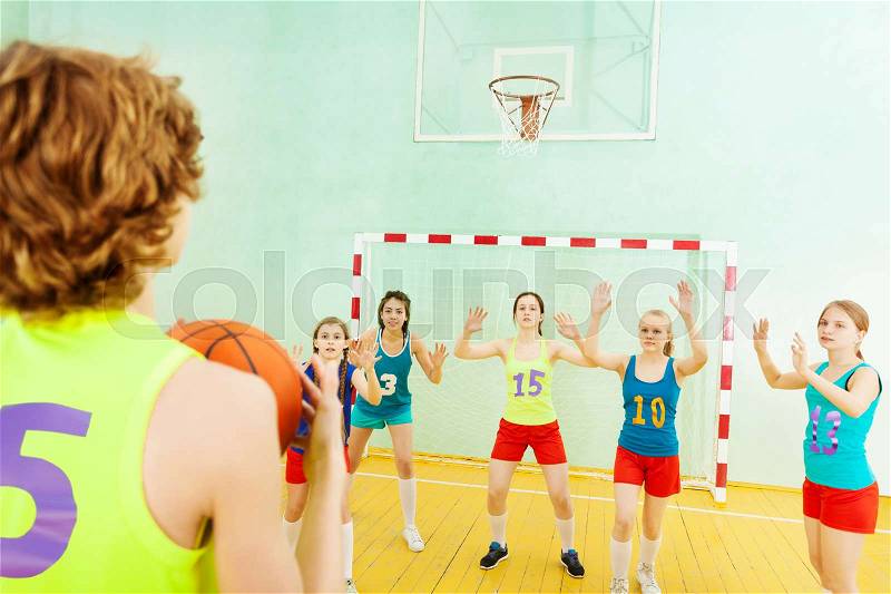 Portrait of basketball player throwing the ball into the basket while his opponents defending the hoop, stock photo