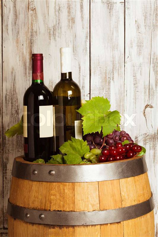 Bottles of wine on the oak barrel over old shabby wooden background, stock photo