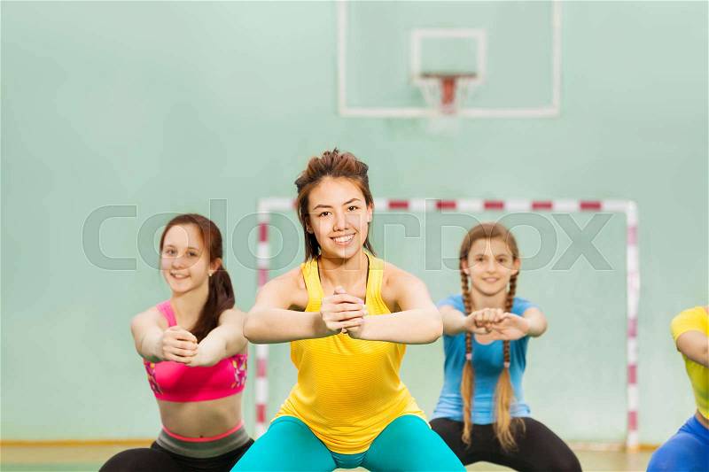 Portrait of happy Asian teenage girl in sportswear doing gymnastics with her friends in gymnasium, stock photo