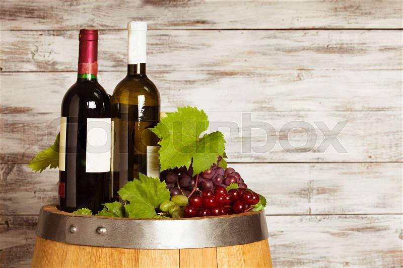 Bottles of wine on the oak barrel over old shabby wooden background, stock photo