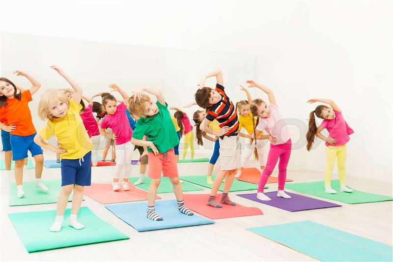 Group of happy kids, 5-6 years old girls and boys, doing side bending exercises in gym, stock photo