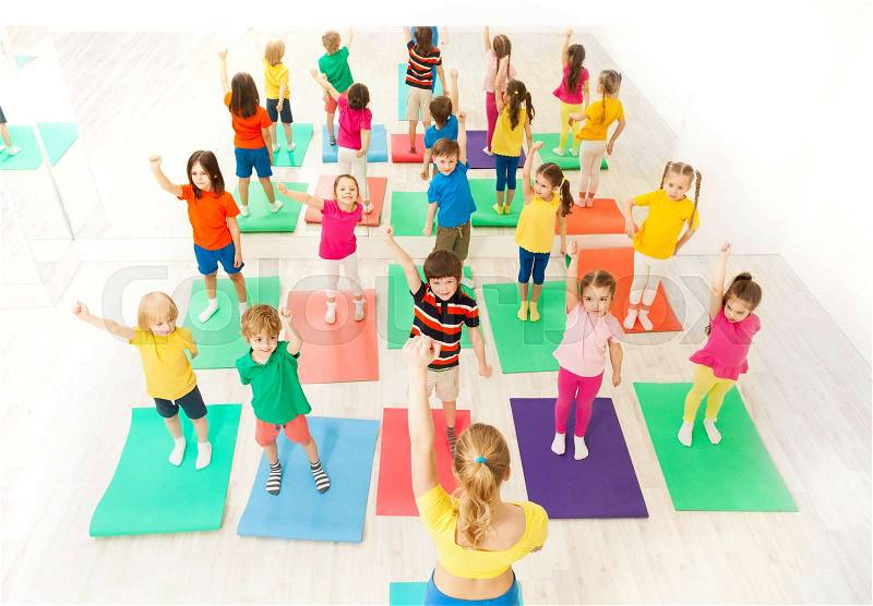 Top view picture of gymnastics group session for kids with female instructor in gym, stock photo