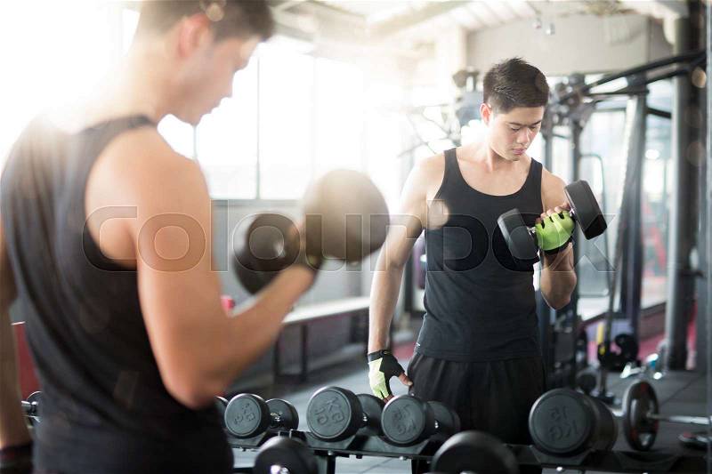Glass mirror of asian man under weight training in Fitness center, stock photo