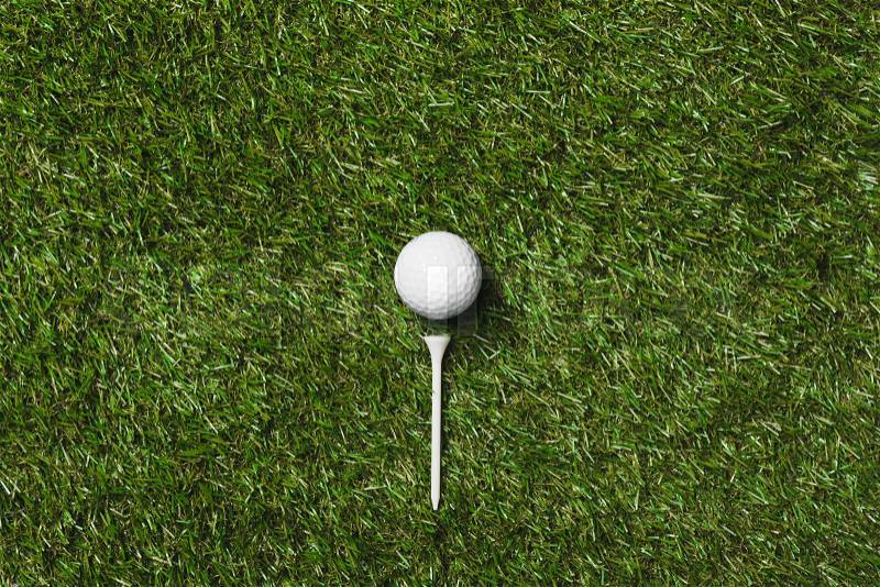 Top view of golf ball and tee on grass field, stock photo