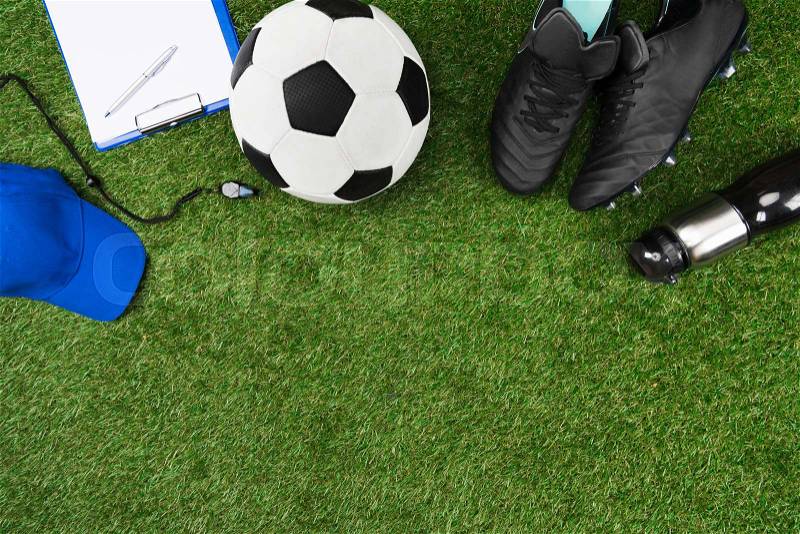 Top view of clipboard with soccer ball and boots on grass, stock photo