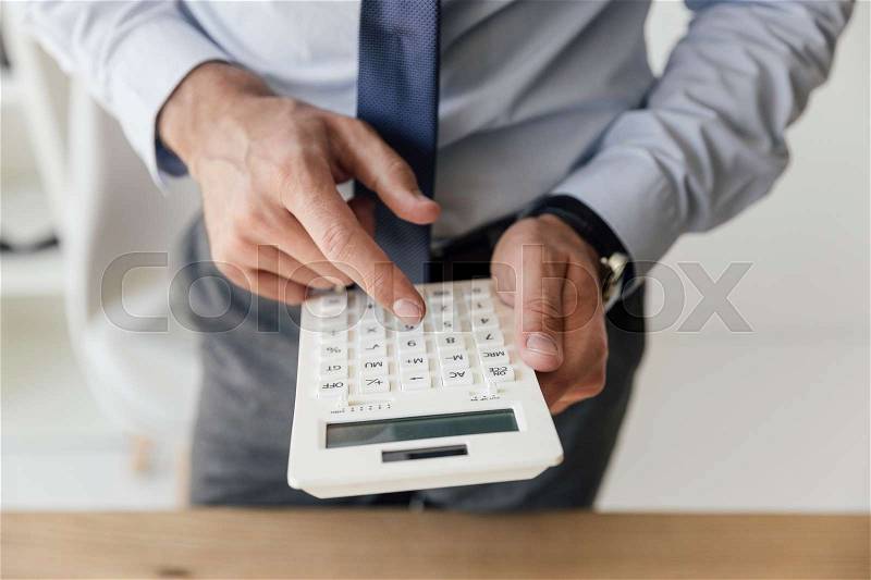 Close up view of businessman making counts on calculator in hands , stock photo