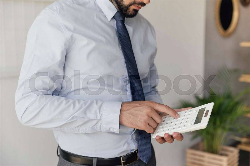 Partial view of businessman making counts on calculator in hands, stock photo