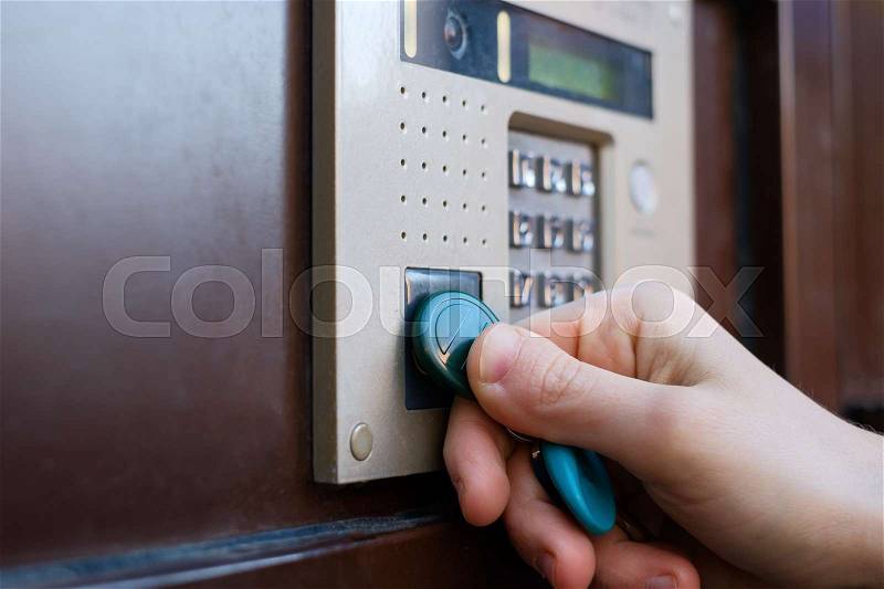 The girl opens the front door with a magnetic tablet. Doorphone as a means of security against robbery, stock photo