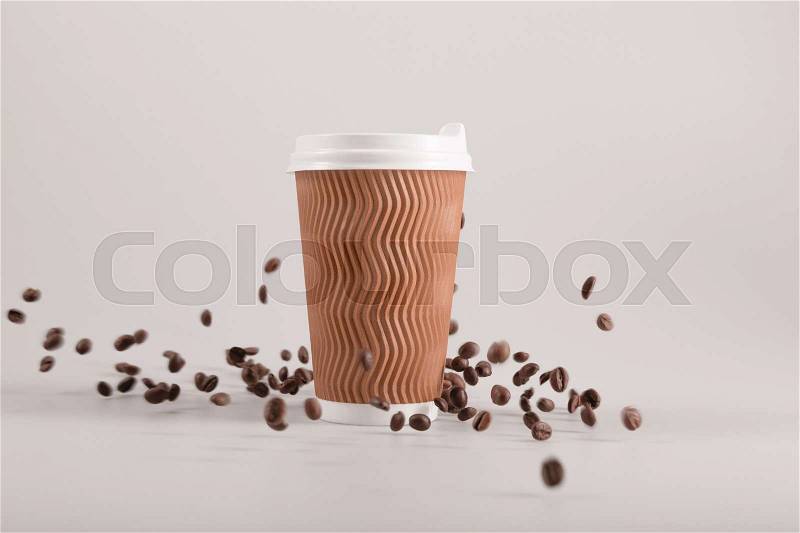Disposable coffee cup with falling coffee grains isolated on beige, stock photo