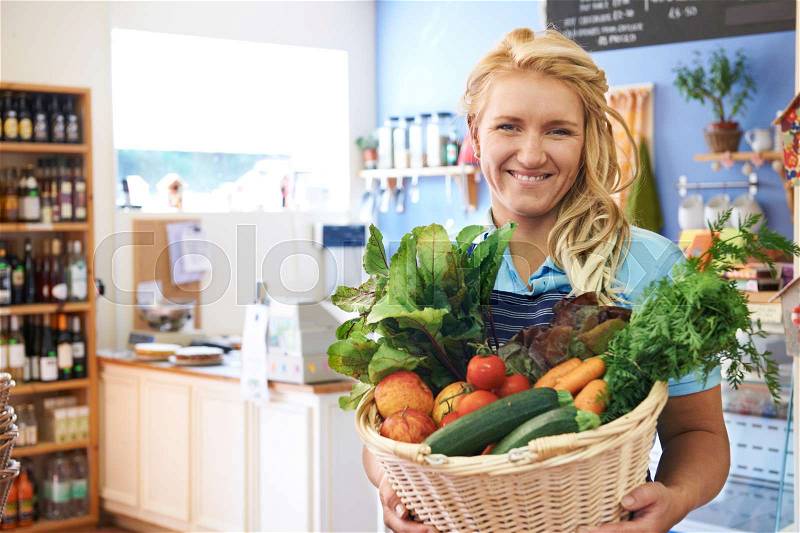Woman Working In Shop With Basket Of Fresh Produce, stock photo