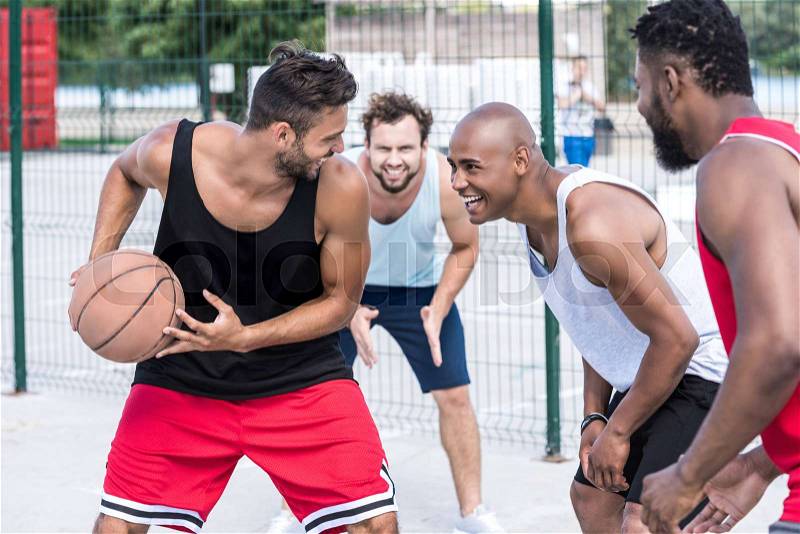 Multiethnic group of basketball players playing basketball on court, stock photo