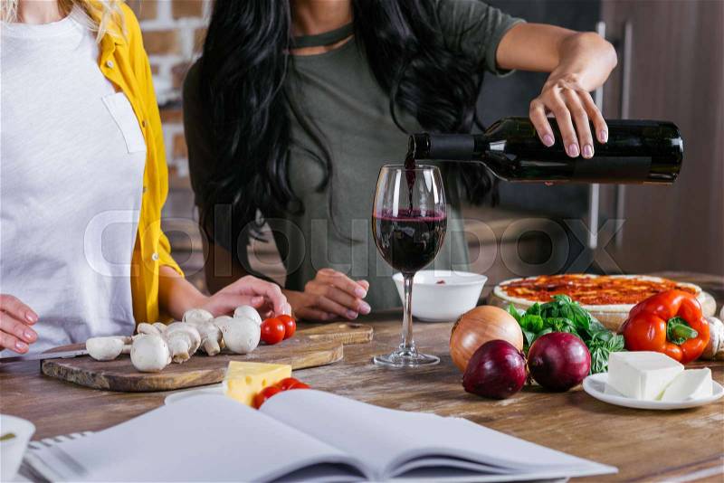 Cropped shot of women drinking wine while cooking pizza together , stock photo