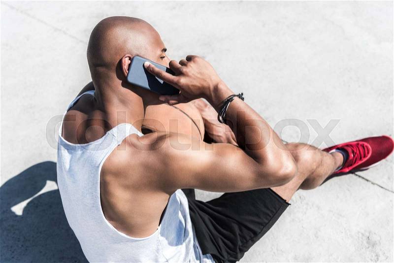 Side view of african american man talking on smartphone on court, stock photo