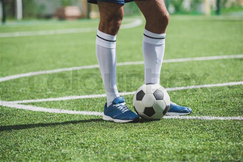 Cropped shot of soccer player standing on soccer pitch with ball, stock photo